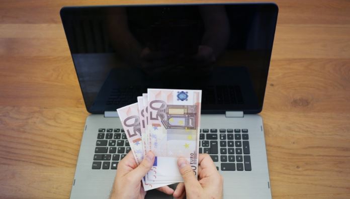 Laptop mit Hand und vielen 50 Euro Scheinen